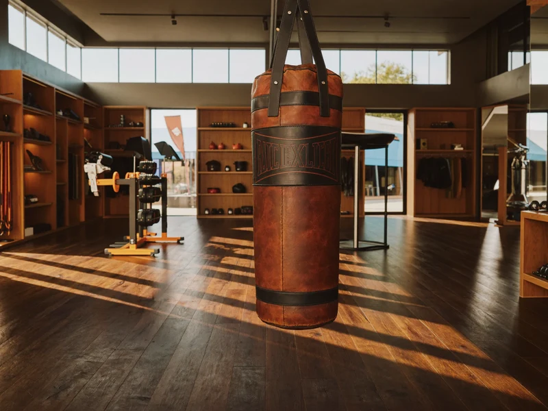 Helles, aufgeräumtes Fitness- und Fightshop-Interieur mit Boxsack, Regalen und Holzboden im Tageslicht