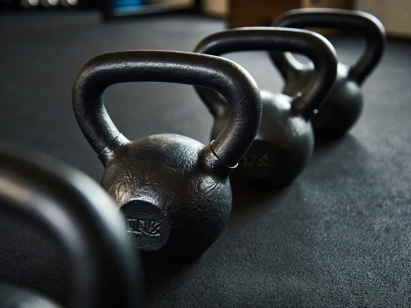 Gusseiserne Kettlebells in aufsteigenden Größen auf Gummiboden, aus niedriger Perspektive